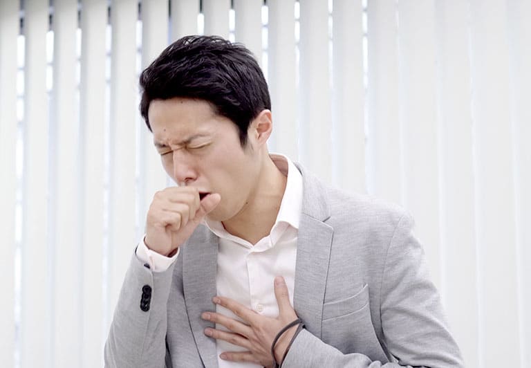 咳き込み口元と胸に手をあてる男性